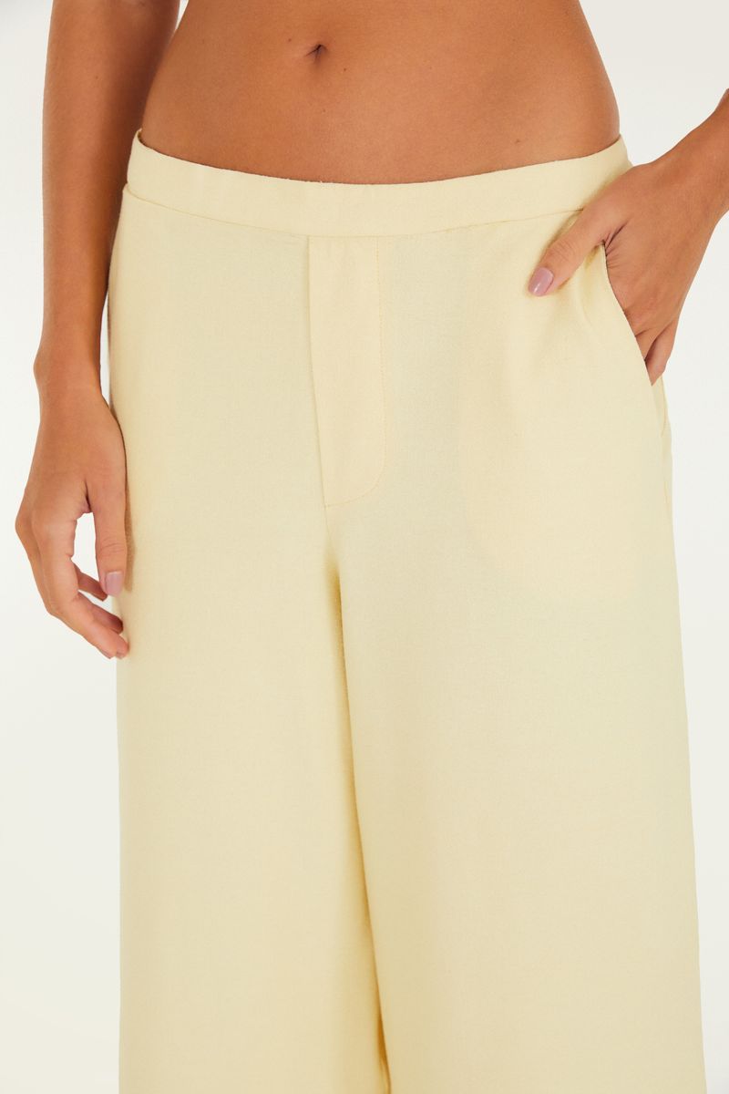 Imagen trasera del pantalón ancho en color beige, destacando la pretina y el ajuste.