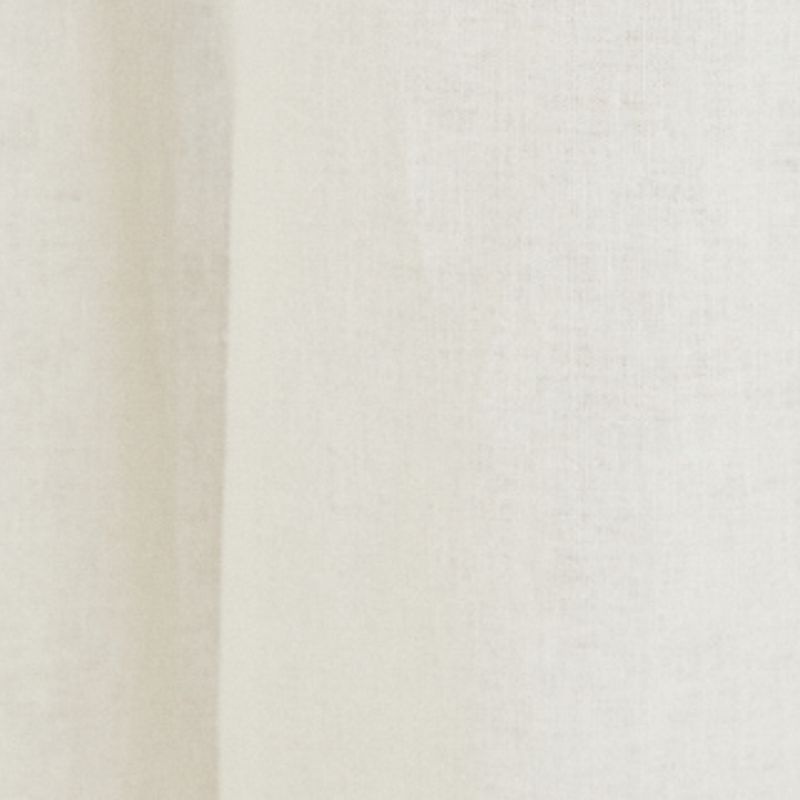 Detalle del tejido beige del pantalón amplio de sastrería.