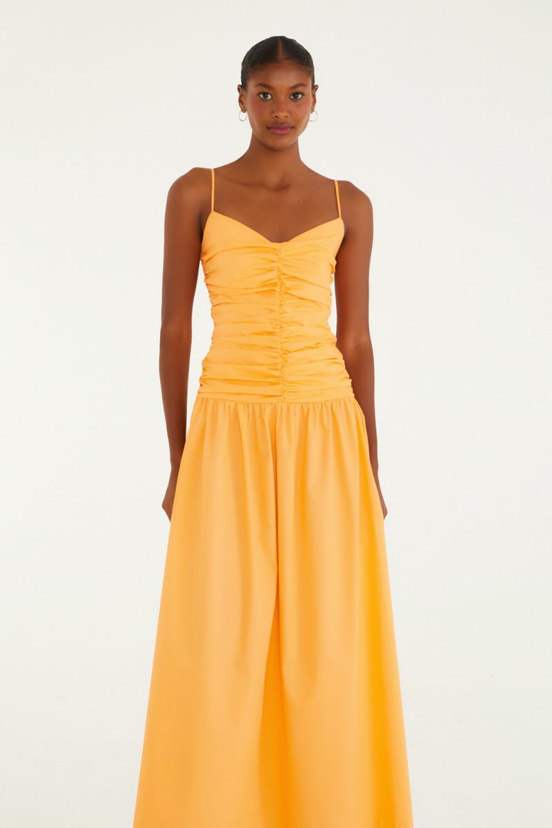 Vestido amarillo con fruncido en la parte delantera, tirantes delgados y falda larga.