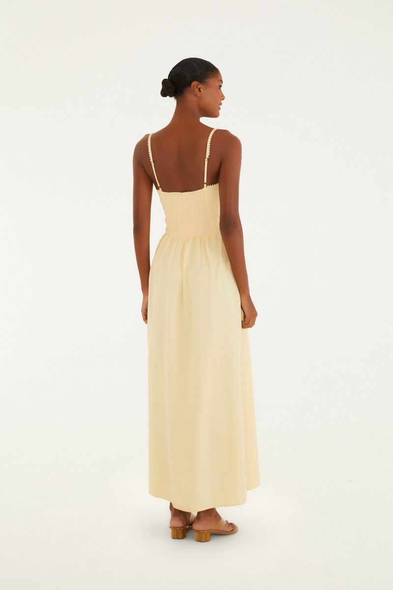 Imagen de un vestido largo con tirantes y lazada frontal, visto de lado.