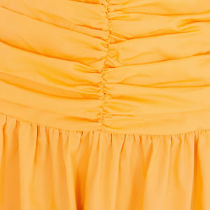 Detalle del fruncido en la parte delantera del vestido amarillo, mostrando el acabado y textura del tejido.
