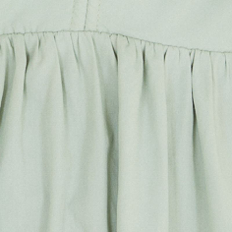 Primer plano de la tela y el acabado del dobladillo del vestido en tono verde claro.