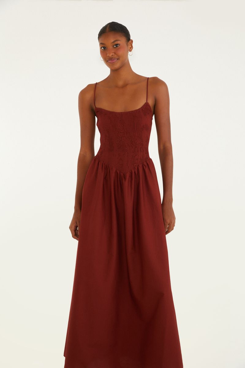Vestido largo en tono terracota con tirantes delgados y detalle de elástico ahumado en el corpiño, visto de lado.