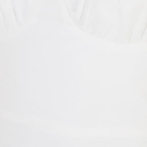 Close-up de la tela del vestido blanco con tirantas delgadas y diseño balón.