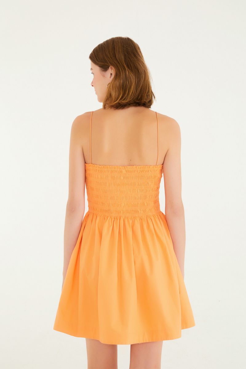 Vista trasera del vestido corto con elástico y tirantes en tono naranja.