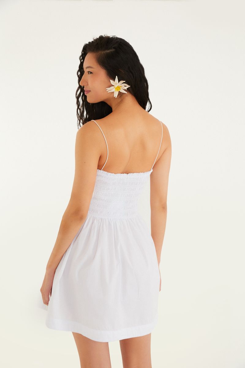 Modelo usando el vestido corto blanco con elástico y tirantes, vista trasera.