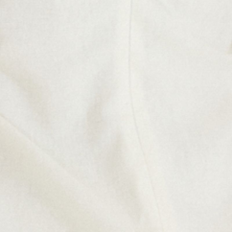 Detalle de la tela blanca del vestido corto, mostrando su textura.