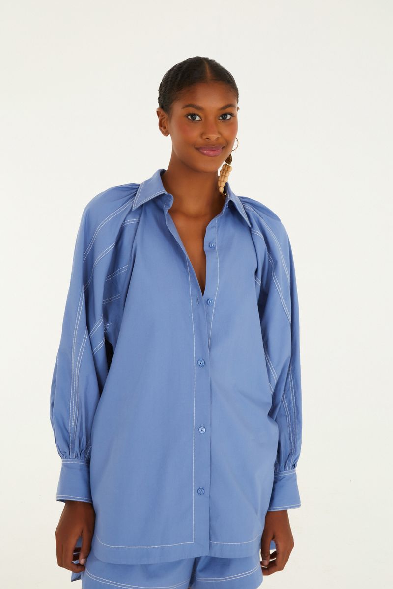 Camisa azul con mangas voluminosas y pespuntes decorativos vista de frente.