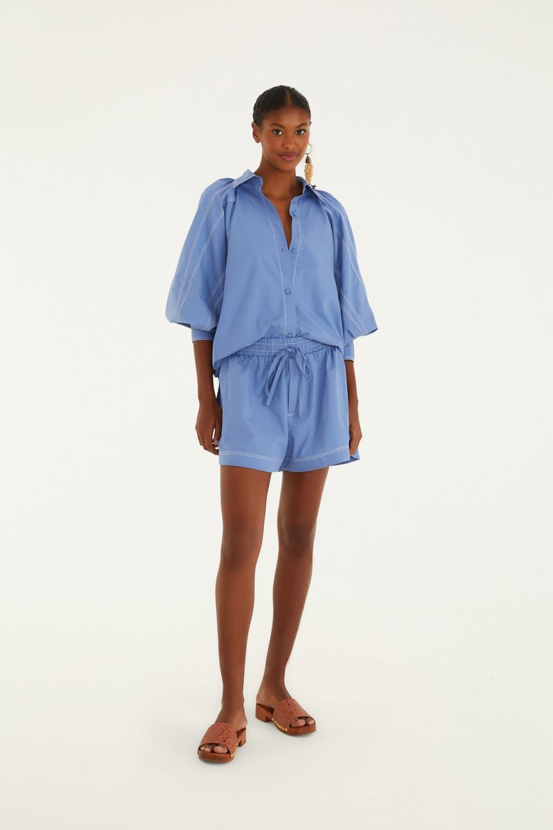 Camisa azul con mangas voluminosas y pespuntes decorativos vista de cuerpo entero.
