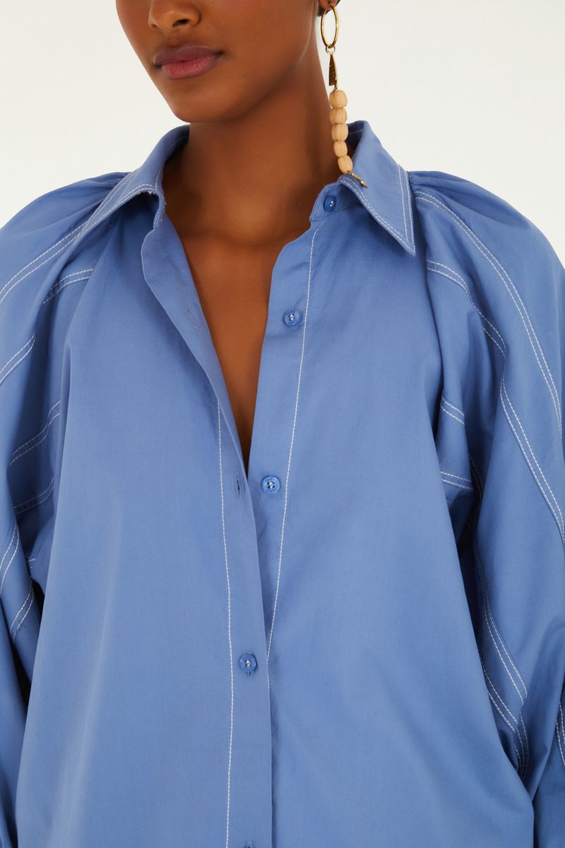 Detalle del cuello y cierre con botones de la camisa azul.