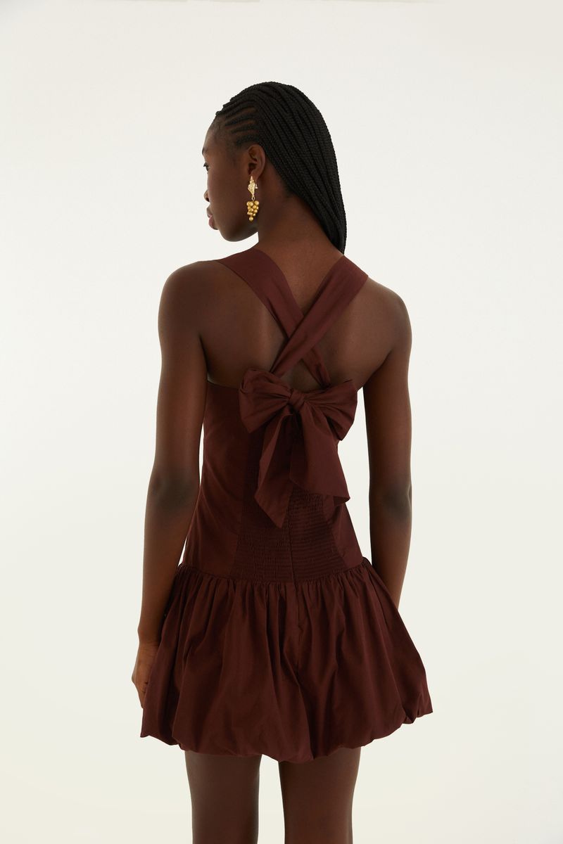 Vista trasera del vestido corto estilo balón con tirantes cruzados y lazo decorativo.
