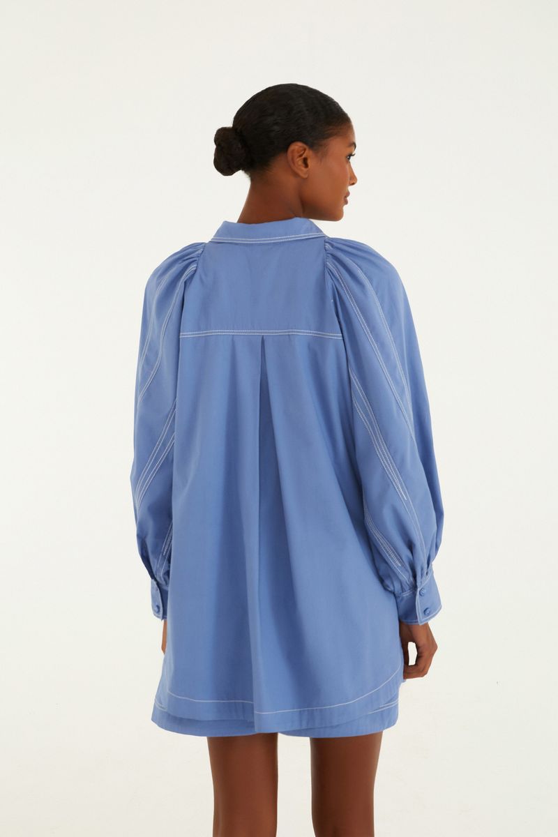 Vista trasera de la camisa azul con pliegues decorativos.