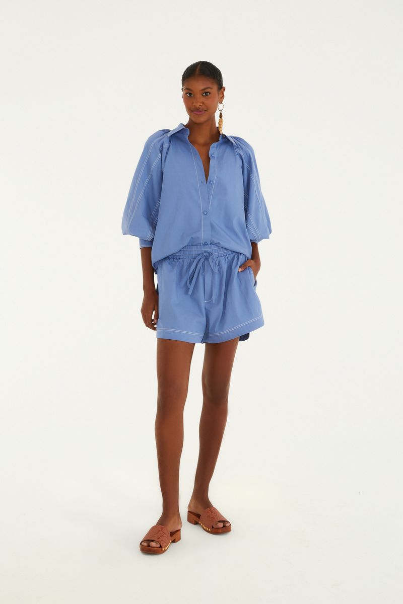 Modelo vistiendo conjunto azul con camisa y short.