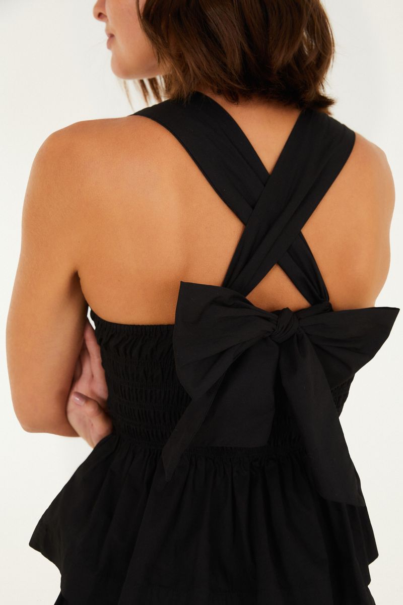 Detalle de la espalda de la blusa negra estilo peplum con lazo.