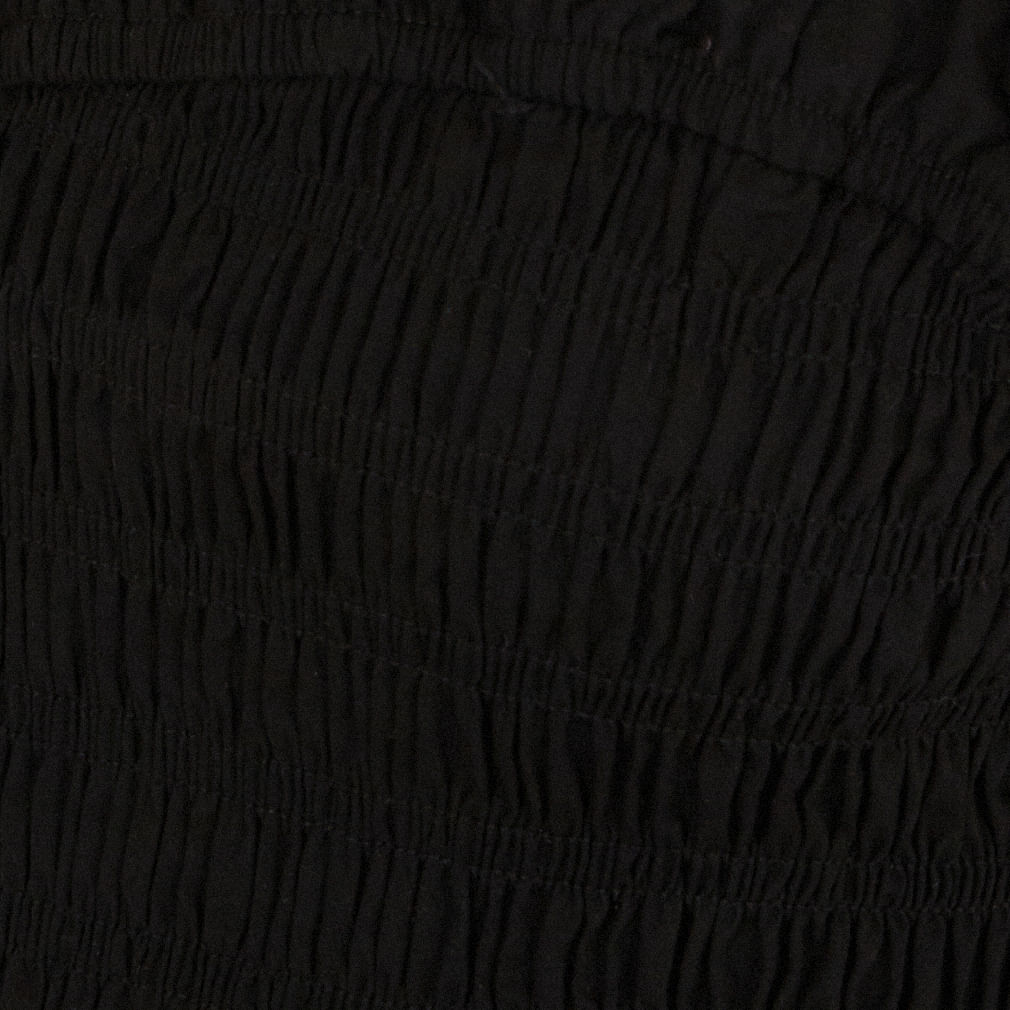 Primer plano del tejido lastex de la blusa negra estilo peplum.