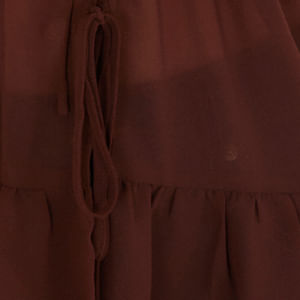 Detalle del lazo frontal de la blusa femenina con volantes y tirantes.