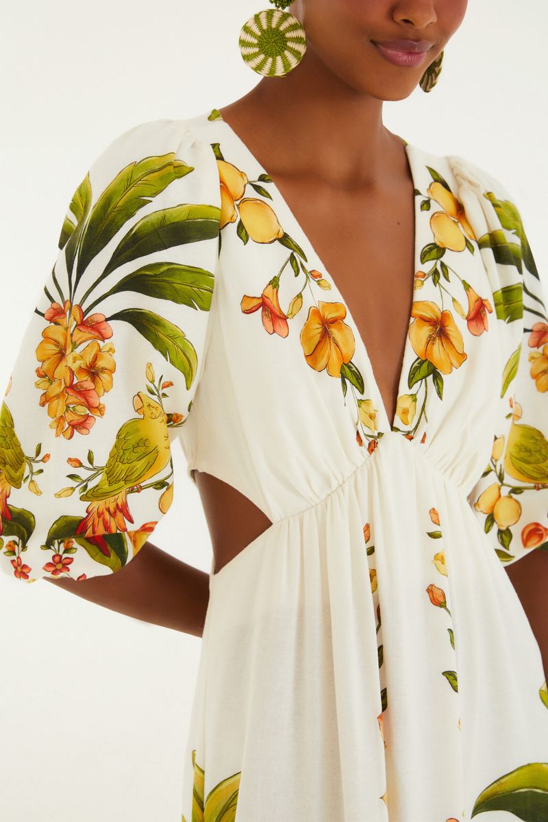 Detalle del cuello en V y mangas infladas con estampado tropical.