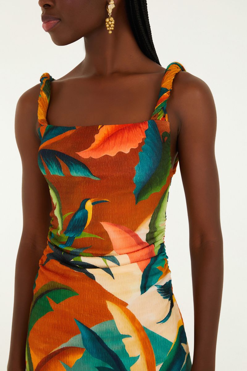 Detalle del corpiño del vestido con estampado tropical sobre fondo naranja.