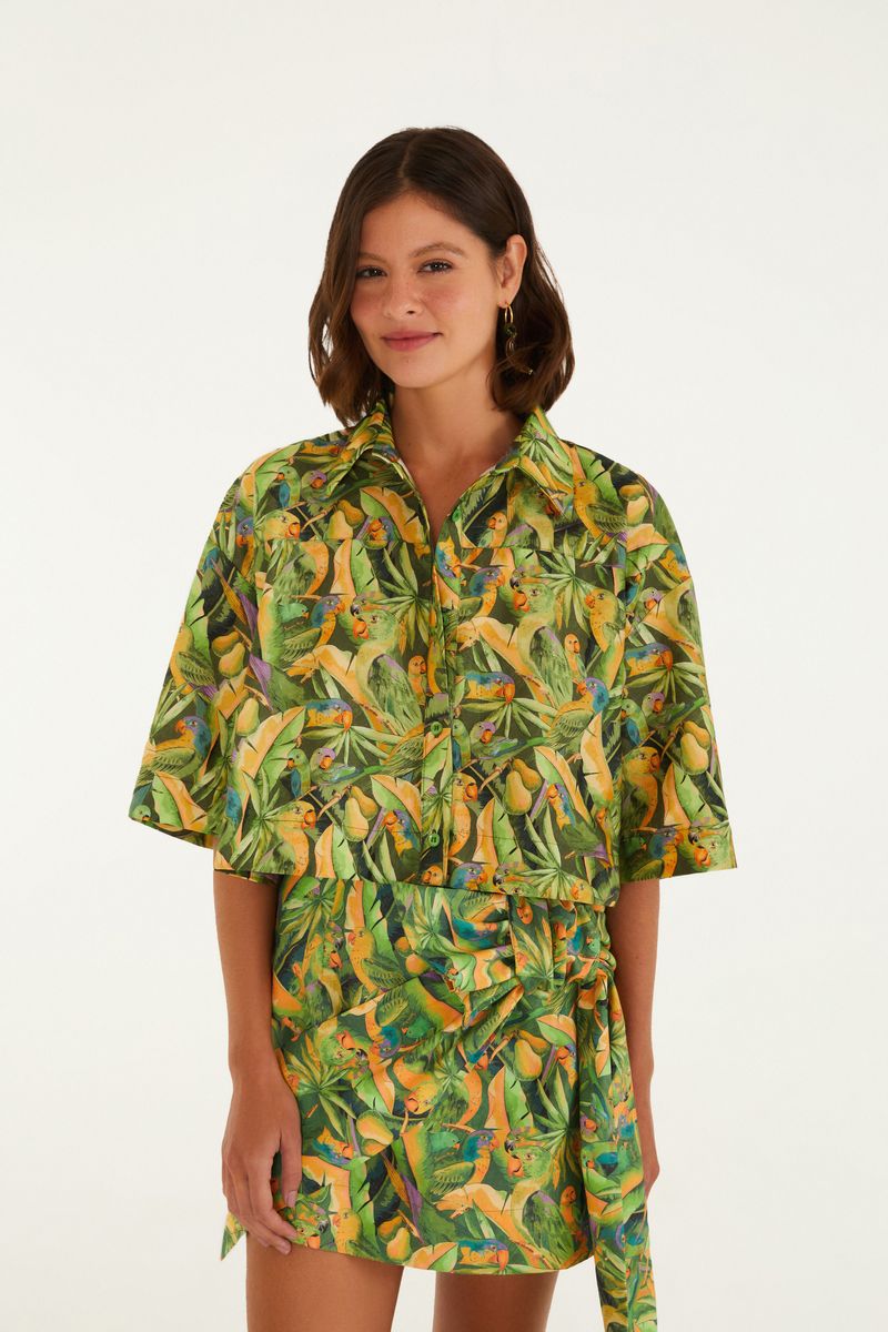 Camisa estampada con tema tropical, vista frontal, destacando aves y follajes.