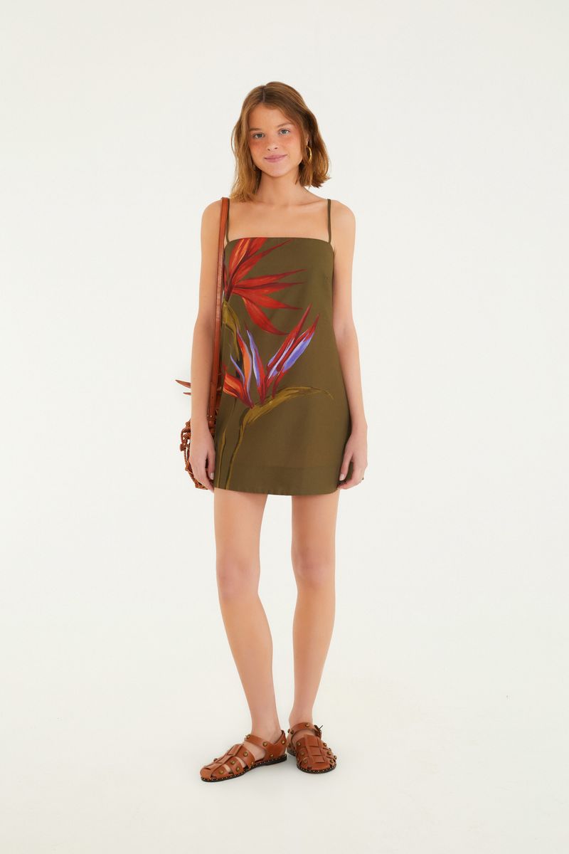 Vestido corto con estampado de flores rojas y azules sobre fondo verde, con tirantes finos y detalle de amarre en la espalda.