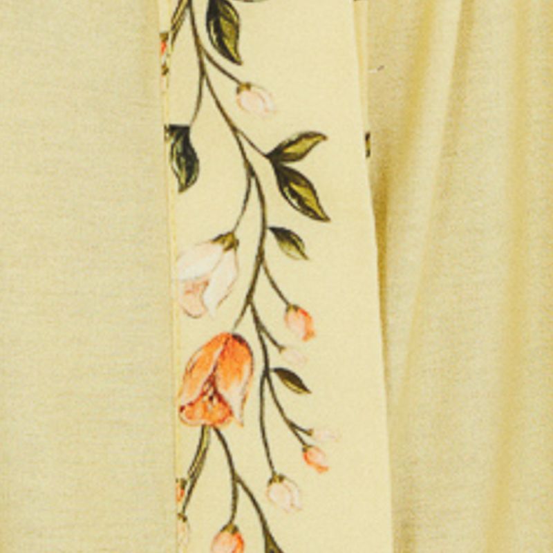 Detalle del estampado del vestido con elementos botánicos y frutas sobre un fondo amarillo claro.