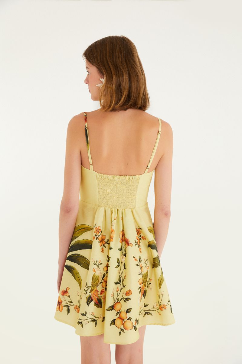 Vista trasera del vestido corto amarillo con estampado floral.