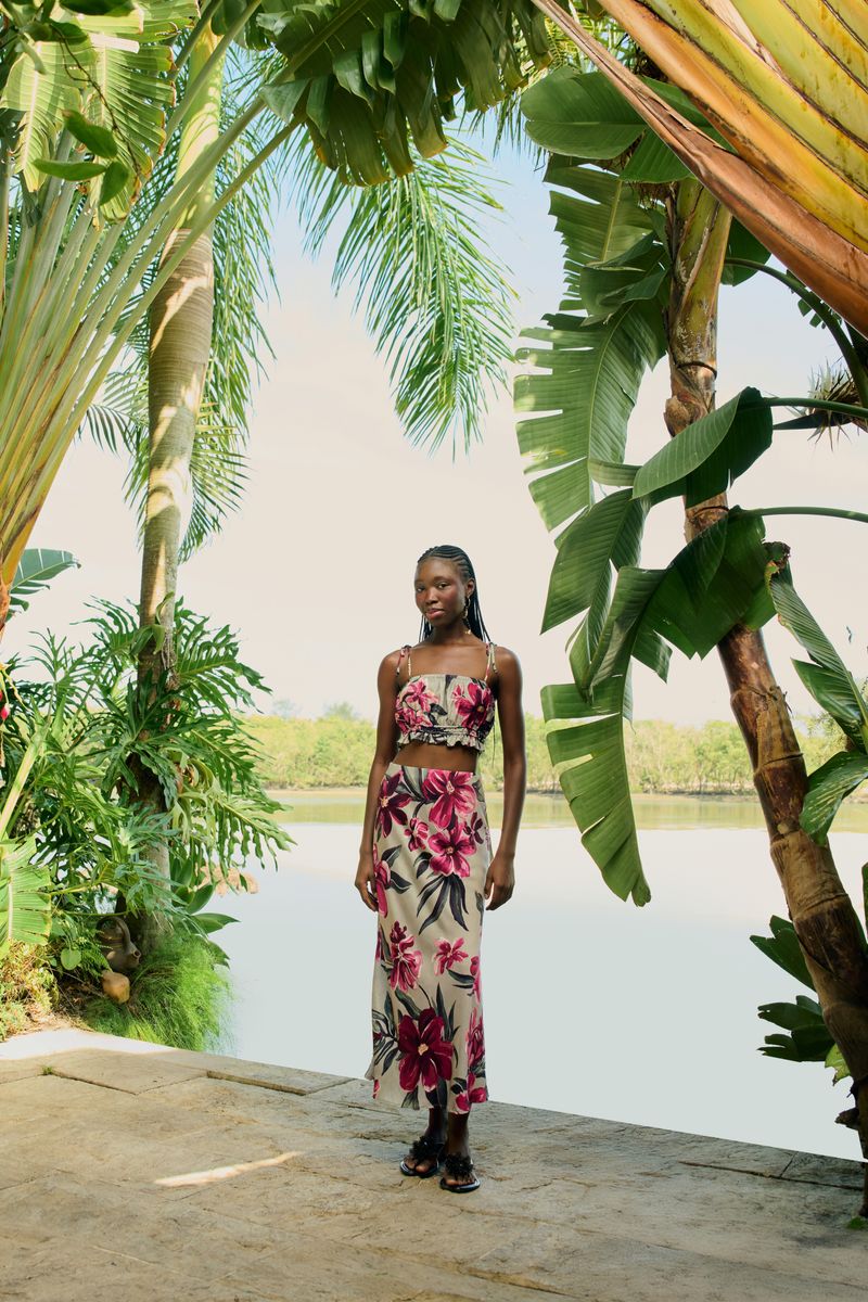 Modelo luciendo una falda larga estampada con flores tropicales en un entorno al aire libre.