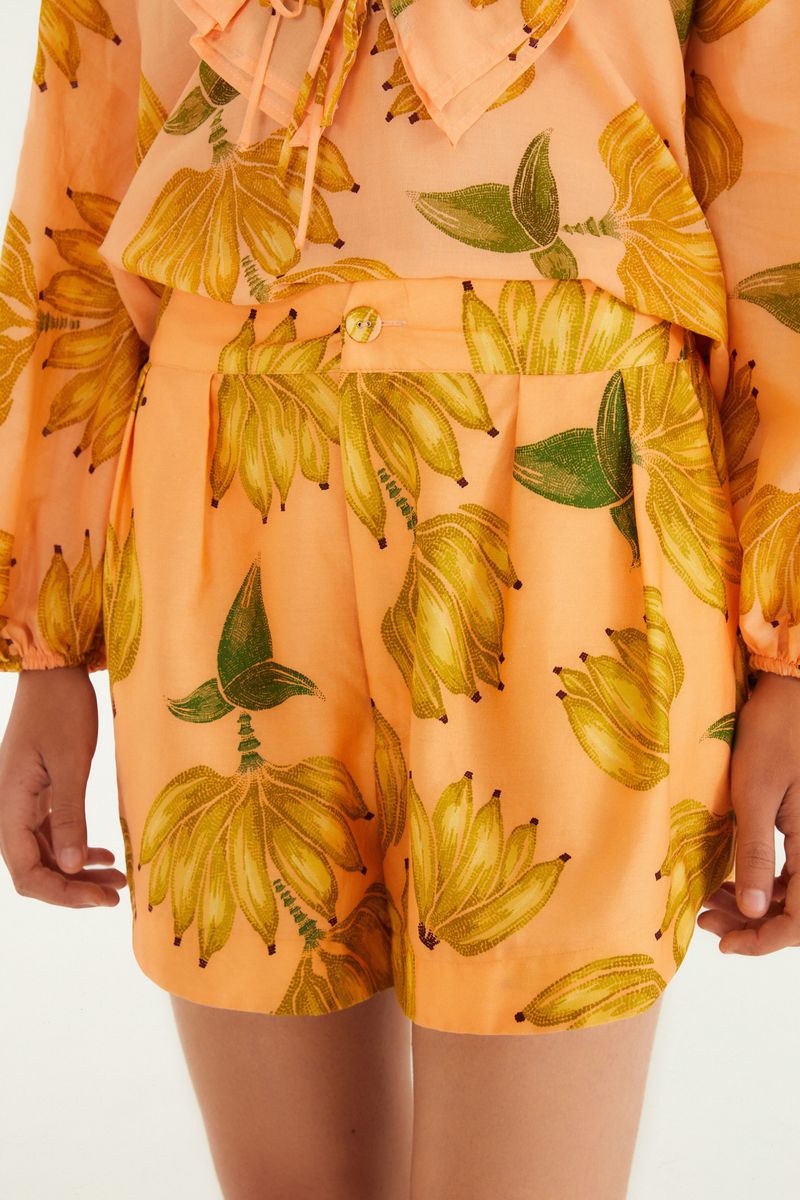 Detalle del short estampado con bananas sobre fondo naranja.