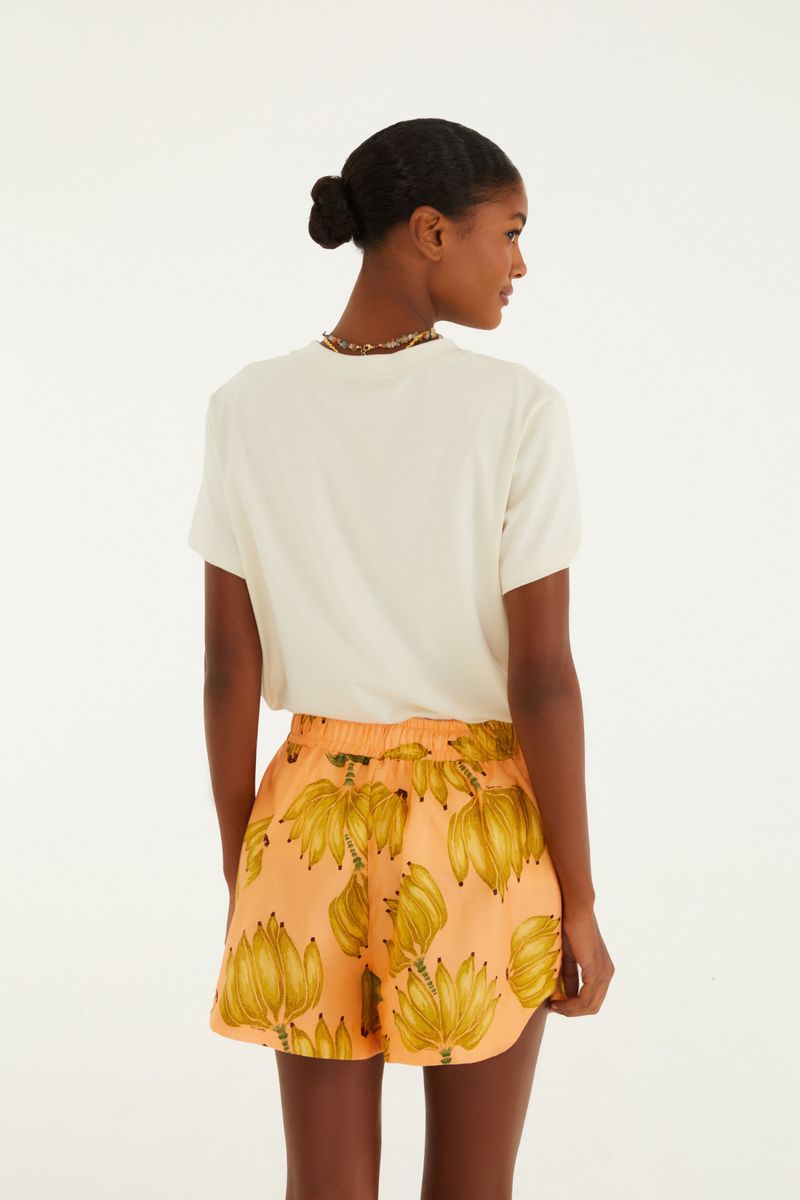 Modelo usando short estampado con tema tropical, combinado con camiseta blanca.