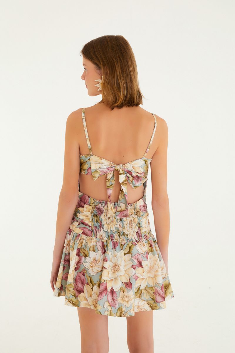 Imagen que muestra la parte trasera de un vestido corto sin tirantes con estampado floral y detalle de amarre.