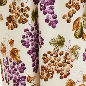 Detalle del estampado botánico de uvas en tonos vibrantes sobre fondo beige.