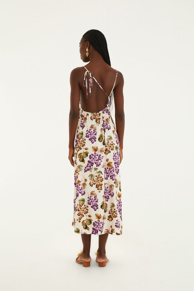 Vestido largo con tirantes finos, estampado de uvas y hojas sobre fondo claro, visto de espaldas.