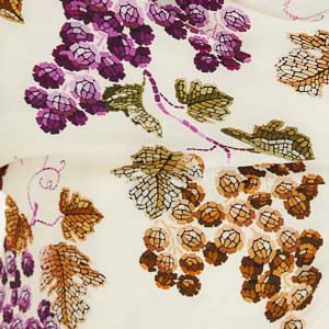 Detalle del estampado de uvas y hojas sobre fondo claro del vestido.