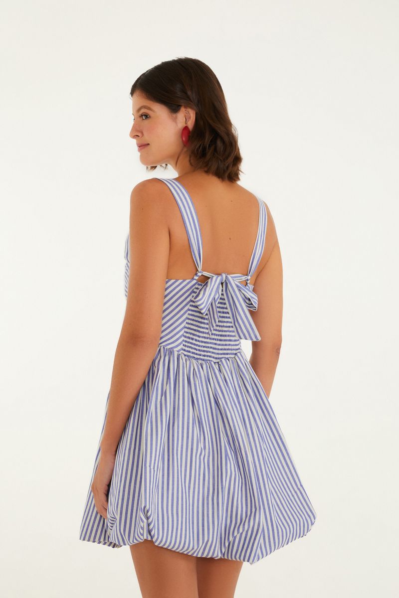 Imagen que muestra un vestido con estampado de rayas azules y blancas, con tirantes anchos y detalle de lazo en la espalda, visto desde atrás.