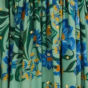 Primer plano del estampado floral del vestido, destacando flores azules y detalles en amarillo sobre fondo verde claro.