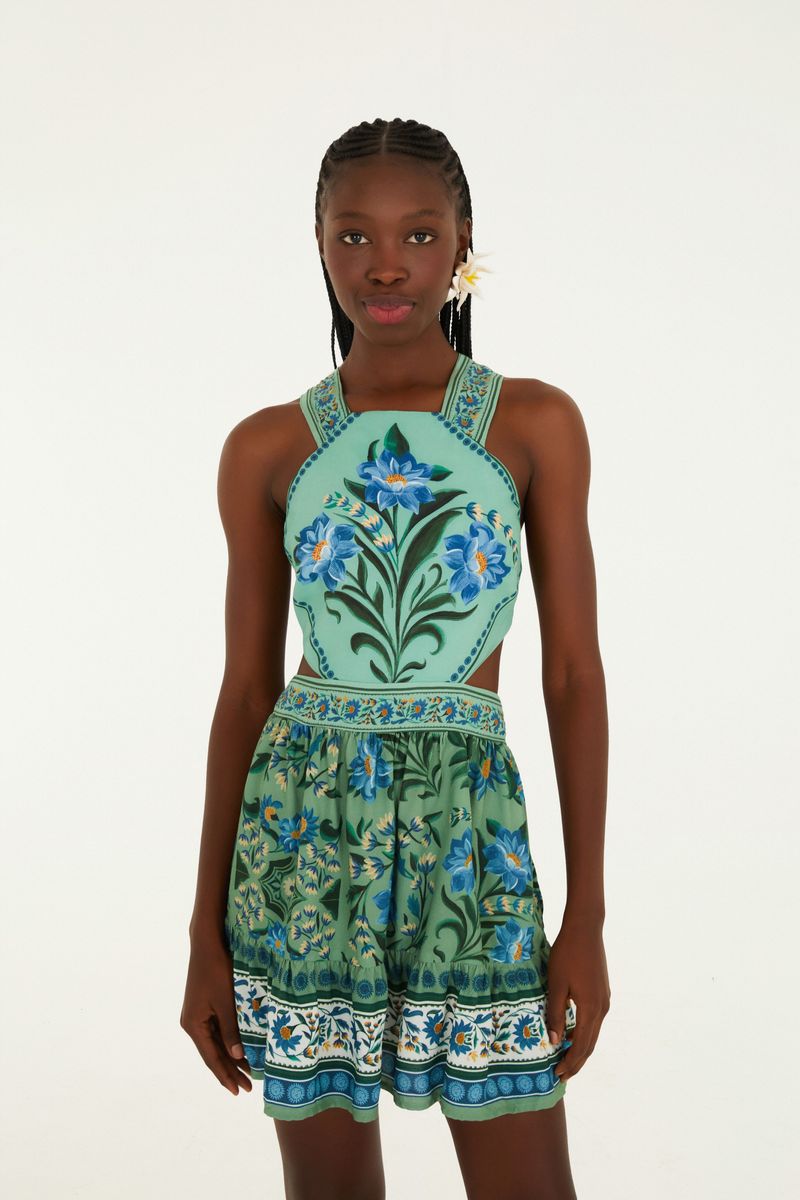 Vestido corto con estampado floral azul y verde, escote alto y tirantes cruzados en la espalda.