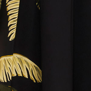 Detalle del estampado tropical de follaje amarillo sobre fondo negro en el pantalón.