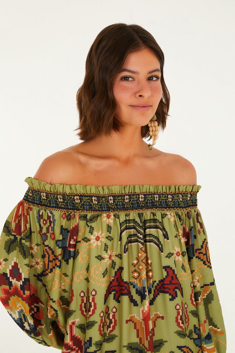 Imagen mostrando un vestido corto con estampado floral y geométrico en tonos vibrantes, con escote hombro a hombro y mangas abullonadas.