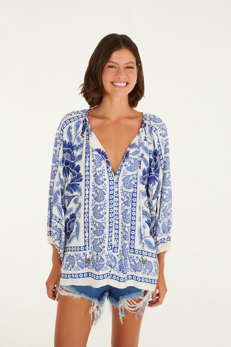 Modelo lleva puesto un short de mezclilla claro con detalles deshilachados, combinado con una blusa estampada azul y blanca.