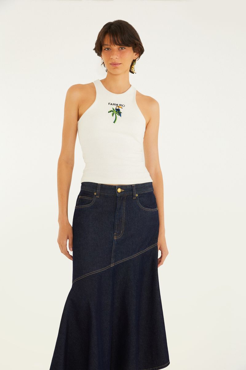 Modelo usando una falda midi de mezclilla mullet diagonal con una blusa blanca, vista frontal.