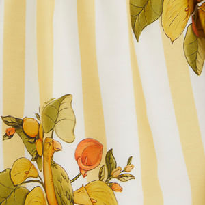 Primer plano del estampado de frutas y rayas del vestido corto, mostrando los detalles vibrantes.