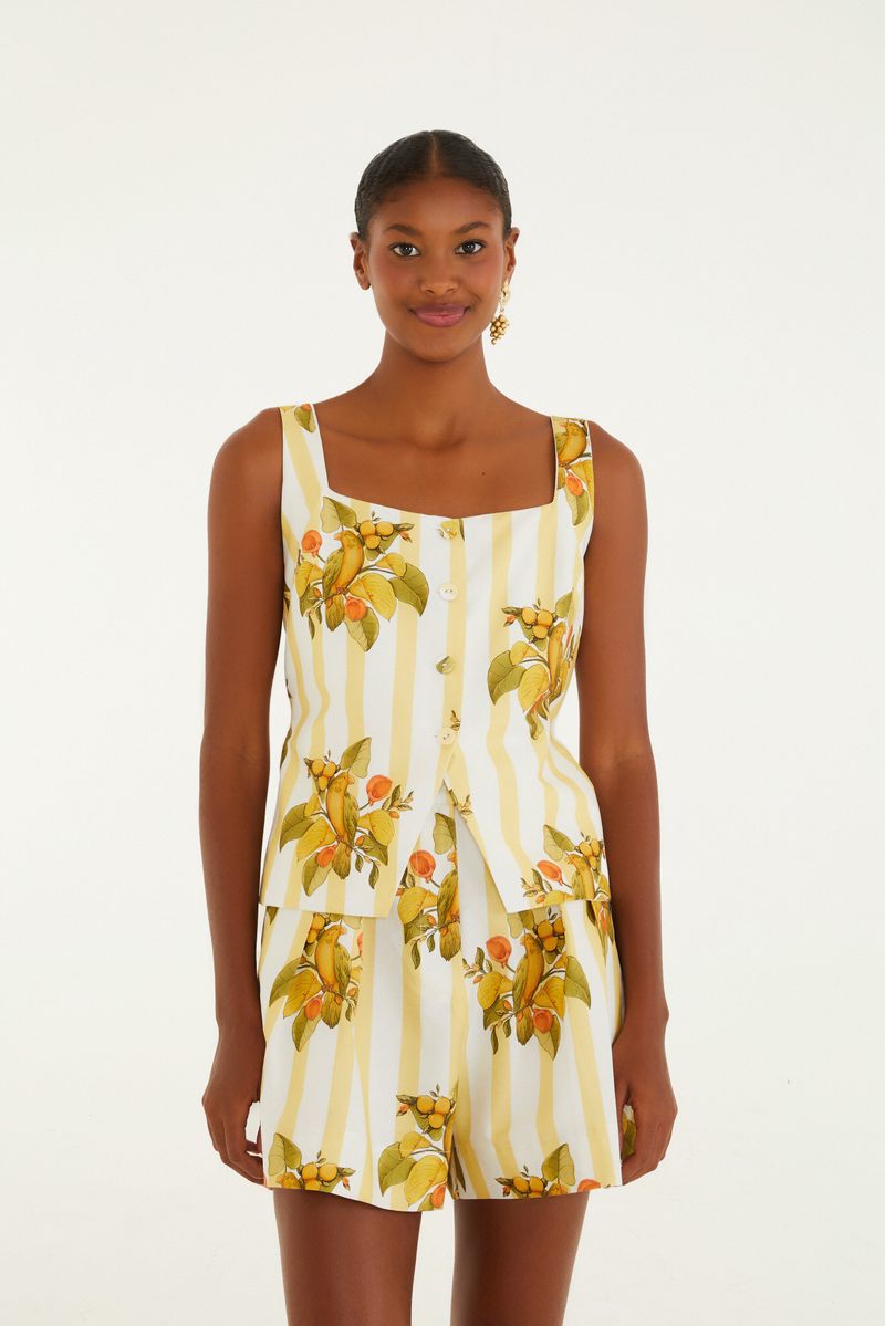 Modelo usando pantalones cortos estampados con pájaros y frutas visto desde atrás.