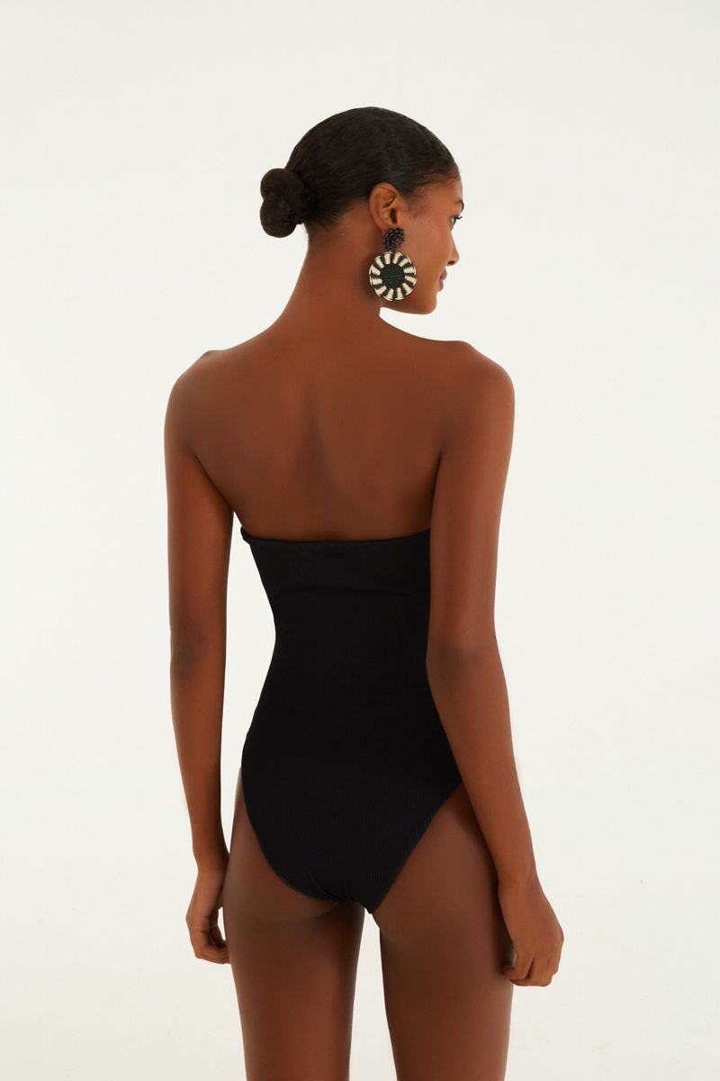 Modelo vistiendo un body negro sin tirantes de canalé, acercamiento al escote.