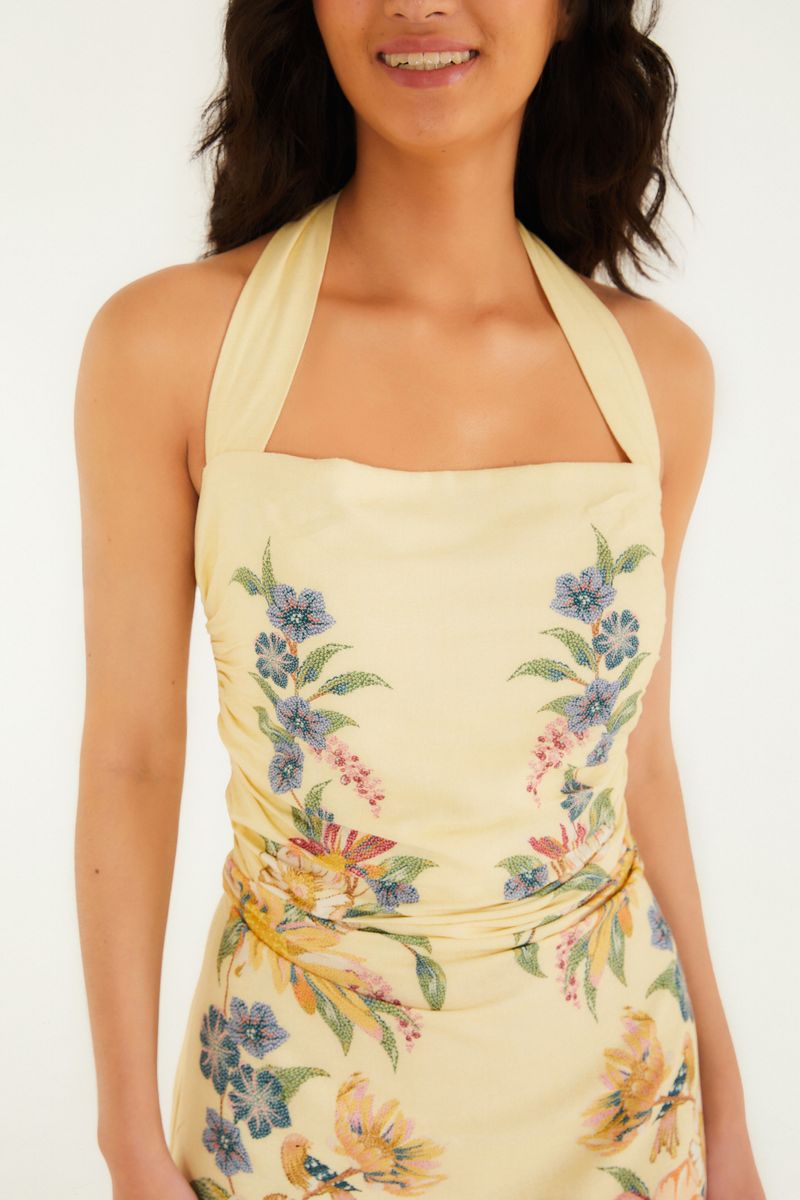 Detalle del escote del vestido corto con estampado floral sobre fondo amarillo.