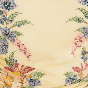 Primer plano del estampado floral del vestido corto sobre fondo amarillo.