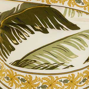 Primer plano del estampado del vestido mostrando hojas verdes y ornamentos dorados.