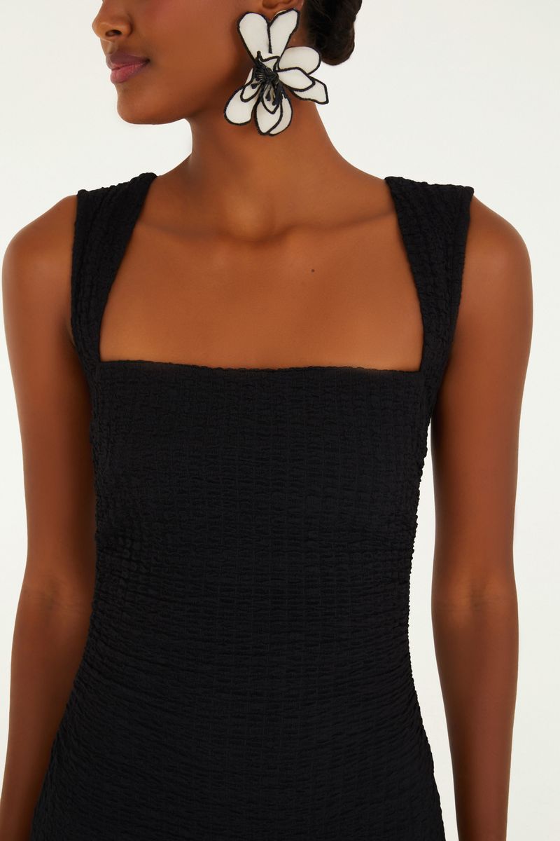 Detalle del escote cuadrado del vestido midi negro con tirantes torcidos, destacando el acabado.