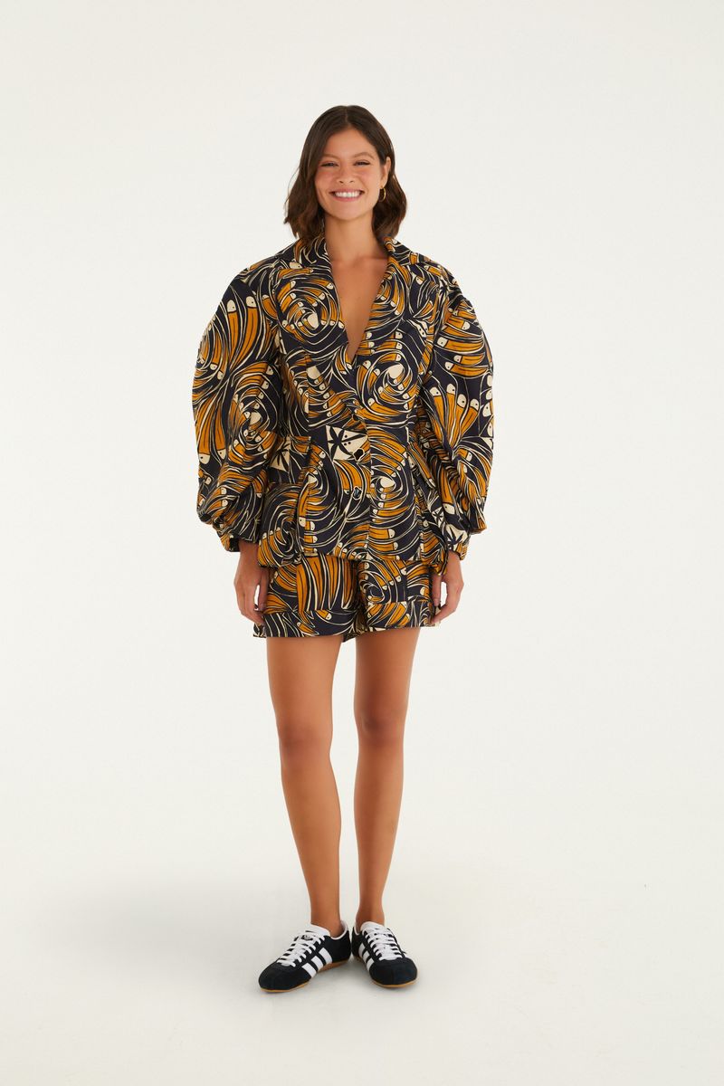 Modelo usando bermuda con diseño tropical de tucanes, combinada con camisa del mismo estampado.