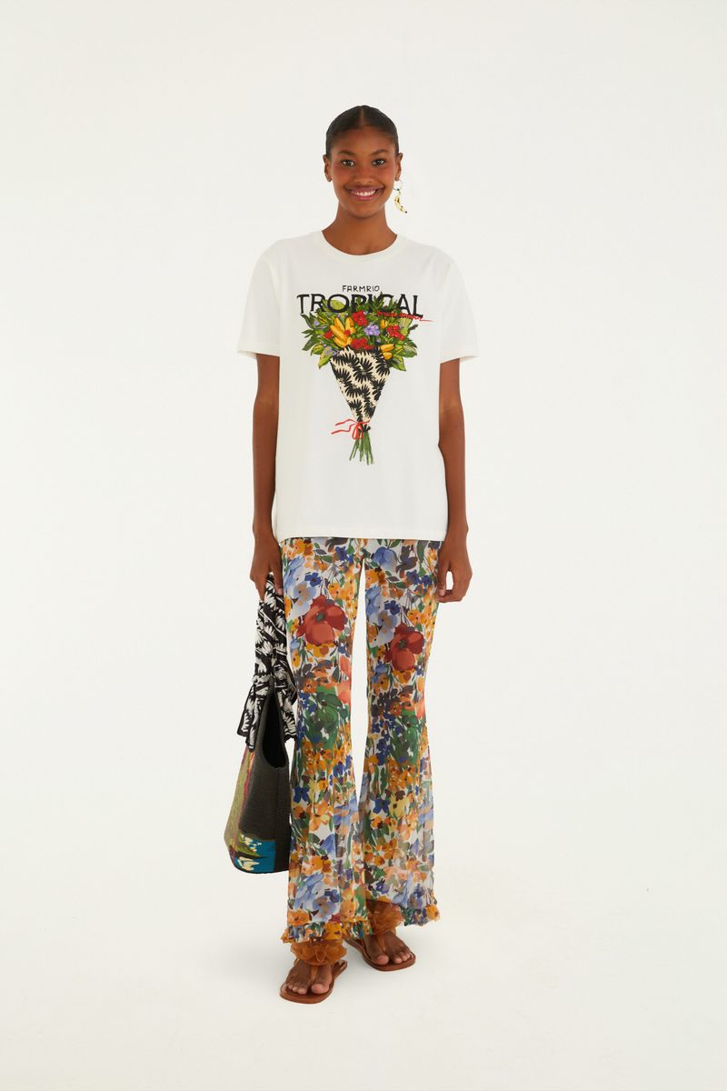 Modelo usando camiseta blanca con estampado tropical y pantalón estampado.