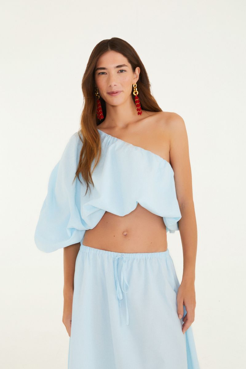 Blusa con diseño de rayas en azul claro, vista frontal mostrando un diseño asimétrico y escote hombros descubiertos.